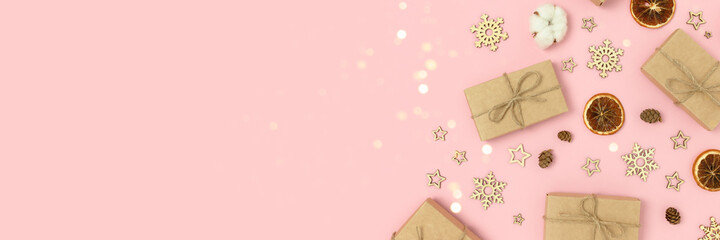 Frame made of natural Christmas decorations and gift boxes on a pink background. Festive banner with copy space.