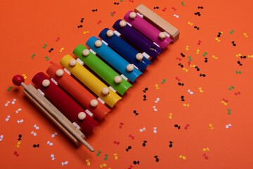 Wooden xylophone in rainbow colors for children an isolated on orange. Paper colorful musical notes...