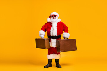 Full length photo of santa claus with beard x-mas christmas eve travel rest hold luggage wear red headwear cap sunglass isolated over bright shine color background