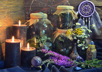 Still life with black candles, bottles and jars with plants and herbs on witch table.  Esoteric, gothic and occult background, Halloween mystic concept