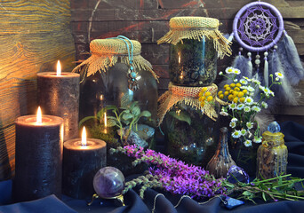 Still life with black candles, bottles and jars with plants and herbs on witch table.  Esoteric,...