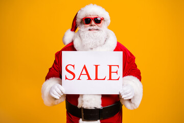 Naklejka premium Portrait of his he nice attractive cheerful cheery confident fat Santa holding in hands board sale advert announcement black Friday isolated bright vivid shine vibrant yellow color background