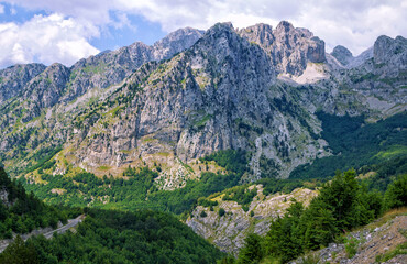 Summer landscape – Albanian mountains, covered with green trees, clouds on blue sky.