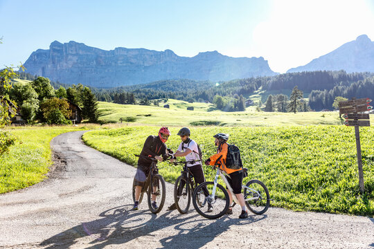 Friends on bicycles using smartphone on road