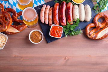 Oktoberfest table with traditional food. Roasted sausages, pretzels, beer, sour cabbage, mustard on...