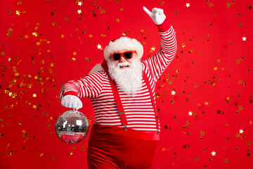 Photo of retired old man grey beard hold vintage disco ball dance funky wear santa x-mas costume suspenders sunglass gloves striped shirt cap isolated red color background - obrazy, fototapety, plakaty