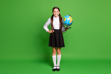 Photo portrait of girl holding globe in one hand other on waist isolated on vivid green colored background