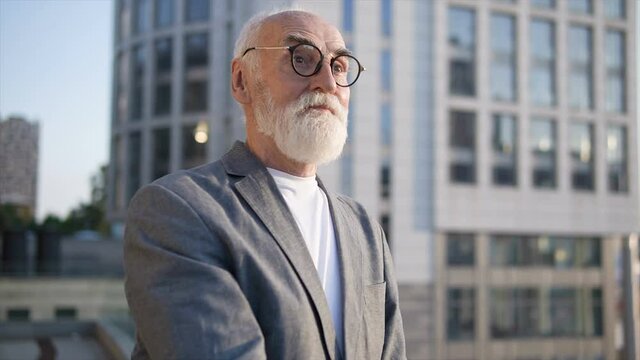 Aged man in eyeglasses and suit standing outdoor, waiting for woman, blind date