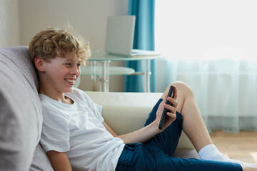 handsome teen boy talk on phone online, video translation on smartphone, look at screen. at home