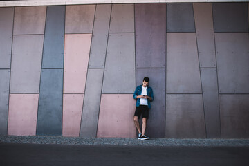 Serious young man leaning on wall