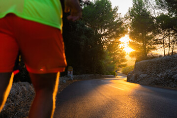 Landscape of a road in the middle of a pine forest with beautiful golden sunset and unfocused man started to run