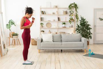 Joyful African American Girl Gesturing Yes Weighing On Scales Indoors