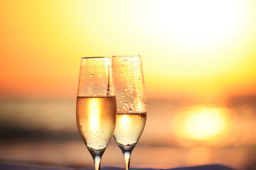 Two glasses of champagne close-up against the background of the sea at sunrise.