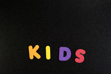 kids word written with colorful foam alphabets on black background children kids school photo