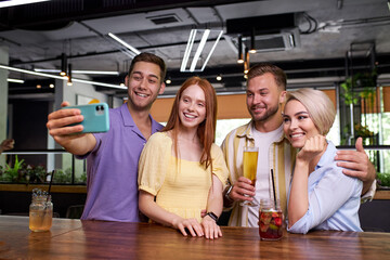 group of american friends taking selfie on mobile phone at bar, man take photo with his dear friends, smile