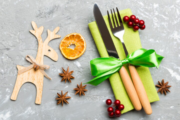 New year set of fork and knife on napkin. Top view of christmas decorations and reindeer on cement background. Close up of holiday family dinner concept