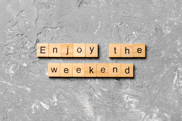 Enjoy the weekend word written on wood block. Enjoy the weekend text on cement table for your desing, Top view concept
