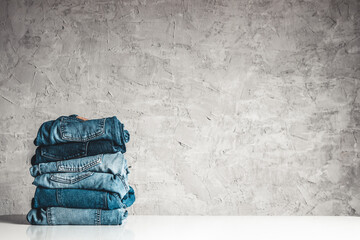 Stack of blue jeans on a gray background