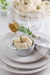 Place setting for Thanksgiving with small white pumkin and rosemary in white