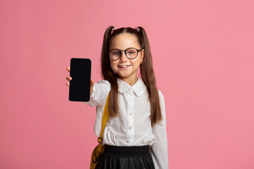 Fototapeta premium Technology and school. Little child in glasses in uniform showing phone
