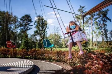 Girl wearing facial mask having fun at amusement park, new reality, summer outdoor