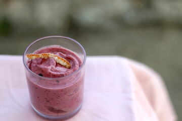 Bowl of banana and berry nice cream, decorated with candied orange peel. Selective focus.