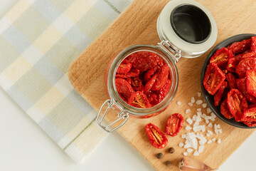 Homemade sun-dried tomatoes in a glass jar, garlic cloves, on a light background. place to copy. selective focus.