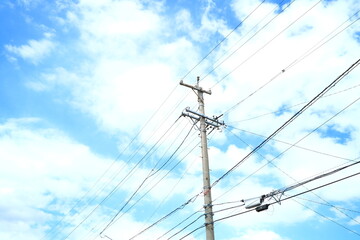 Fototapeta premium 青空と白い雲を背景に撮影した電柱と電線