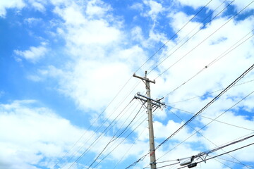 青空と白い雲を背景に撮影した電柱と電線