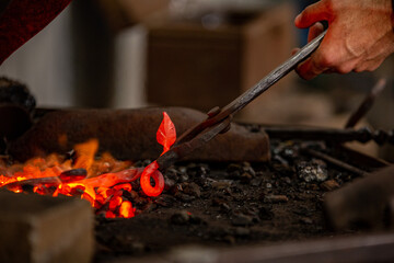A metal piece in the furnace of the forge. A Blacksmith working on a detail