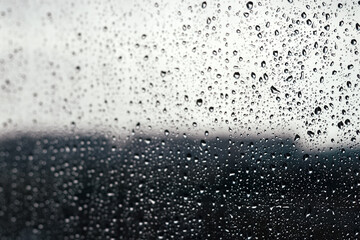 Drops of water on the glass against a blurred dark light gradient background on a rainy cloudy day. Selective focus