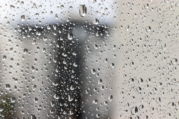 Drops of water on the window glass against a blurred background on a cloudy rainy day