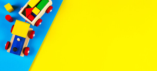 Wooden toy train with colorful blocks on light blue and yellow background. Top view