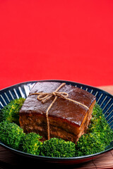 Dong Po Rou (Dongpo pork meat) in a beautiful blue plate with green broccoli vegetable, traditional festive food for Chinese new year cuisine meal, close up.
