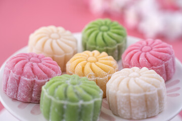 Colorful snow skin moon cake, sweet snowy mooncake, traditional savory dessert for Mid-Autumn Festival on pastel pale pink background, close up, lifestyle.