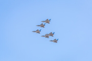 Modern armed military fighter jets flys in formation through the sky.