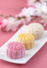 Colorful snow skin moon cake, sweet snowy mooncake, traditional savory dessert for Mid-Autumn Festival on pastel pale pink background, close up, lifestyle.