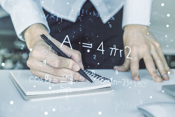 Creative scientific formula hologram with hand writing in notepad on background with laptop,...