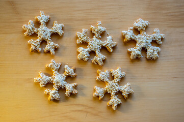 Traditional Czech tasty white painted brown gingerbreads, Christmas snowflakes on wooden table
