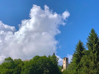 campanile di una chiesa di montagna, che esce dagli alberi
