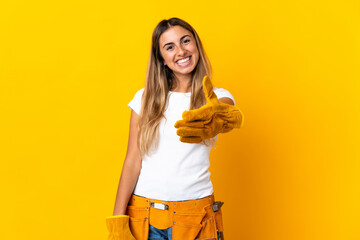 Young hispanic electrician woman over isolated yellow wall shaking hands for closing a good deal