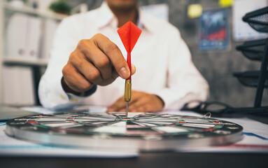 Close up hand of business man holding dart on target to successful goal on table, success and...