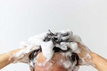 A man washes his head with shampoo on white background, front view