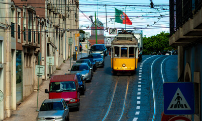 Trambia yellow of the city of Lisbon descends through the street, in the background the flag of Portugal flies