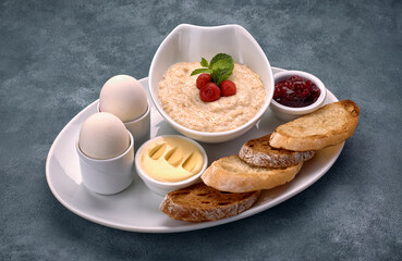 Breakfast of porridge, butter, boiled eggs, jam and toast, croutons