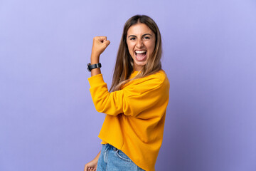 Young hispanic woman over isolated purple background celebrating a victory