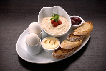 Breakfast of porridge, butter, boiled eggs, jam and toast, croutons