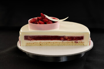 Half or slice of white chocolate mousse and strawberries cake isolated on black background. Copy space. High quality photo. 