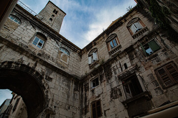 Detalle de ventanas en fachada de piedra con torre sobre arco