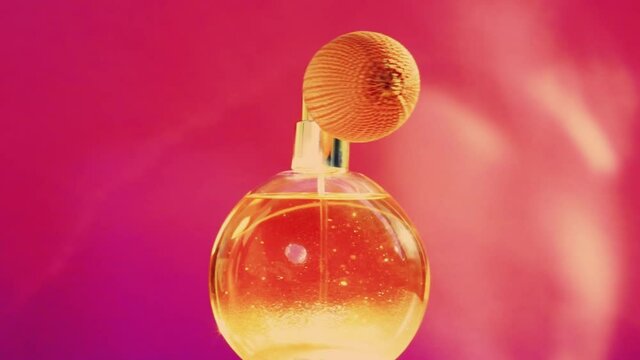 Golden fragrance bottle and shining light flares on pink background, glamorous perfume scent as holiday perfumery product for cosmetic and beauty brand, stock footage